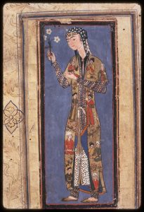 A slender young girl is wearing a long golden robe covered with images of seated and standing noblemen and a cap with long pointy ends hanging on both sides of her face. Her undergarments and skinny shalvars peaking from under her robe are decorated in geometric patterns. The girl is placed against a solid dark background against which her brightly patterned clothing stand out. 