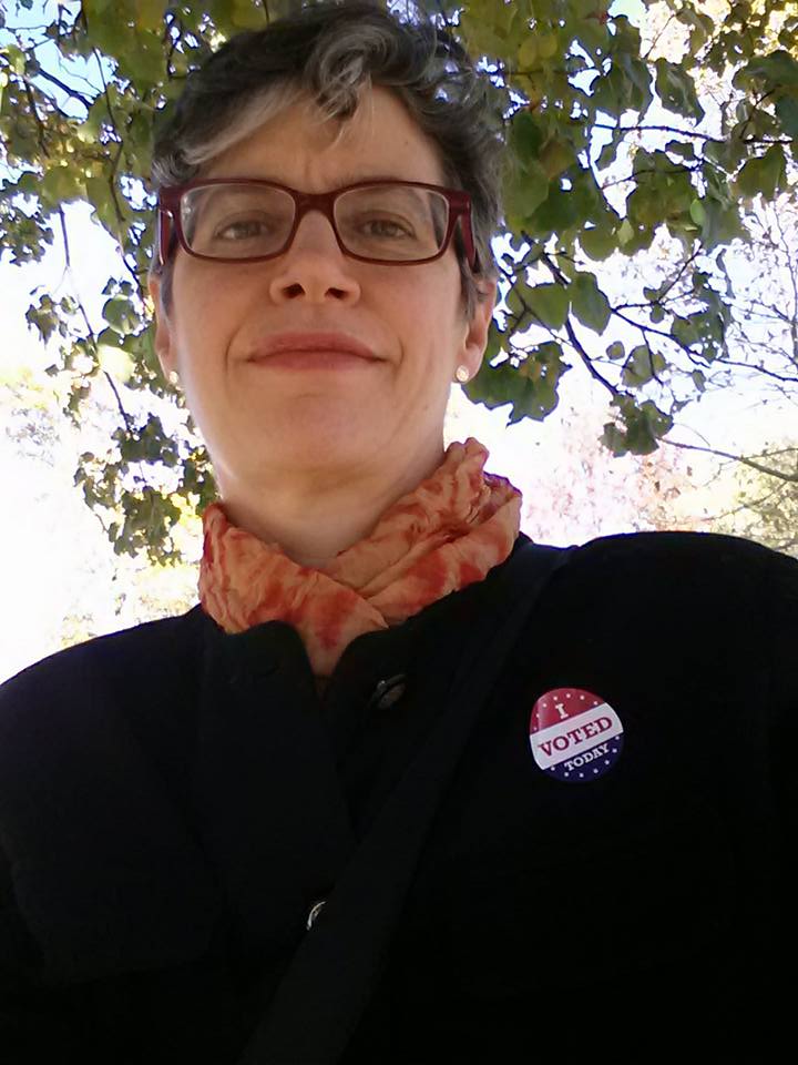 Senior Music Cataloger Anne Adams is posed with a green-leaved tree behind her. She is wearing a black pantsuit with an I Voted Today sticker on the lapel.