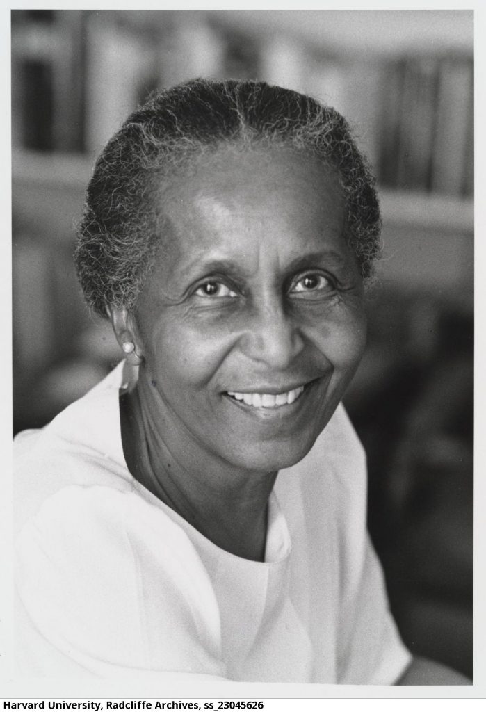 Eileen Southern, a Black woman who was a professor at Harvard University, is depicted. Professor Southern is wearing a white short-sleeved blouse smiles at the camera. Her body is turned away.