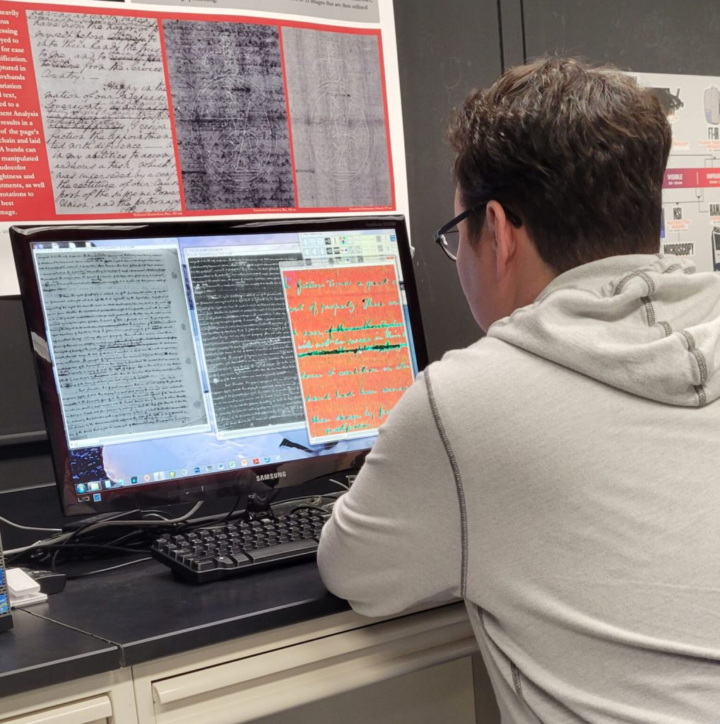 A researcher views a screen showing a handwritten text under various imaging conditions
