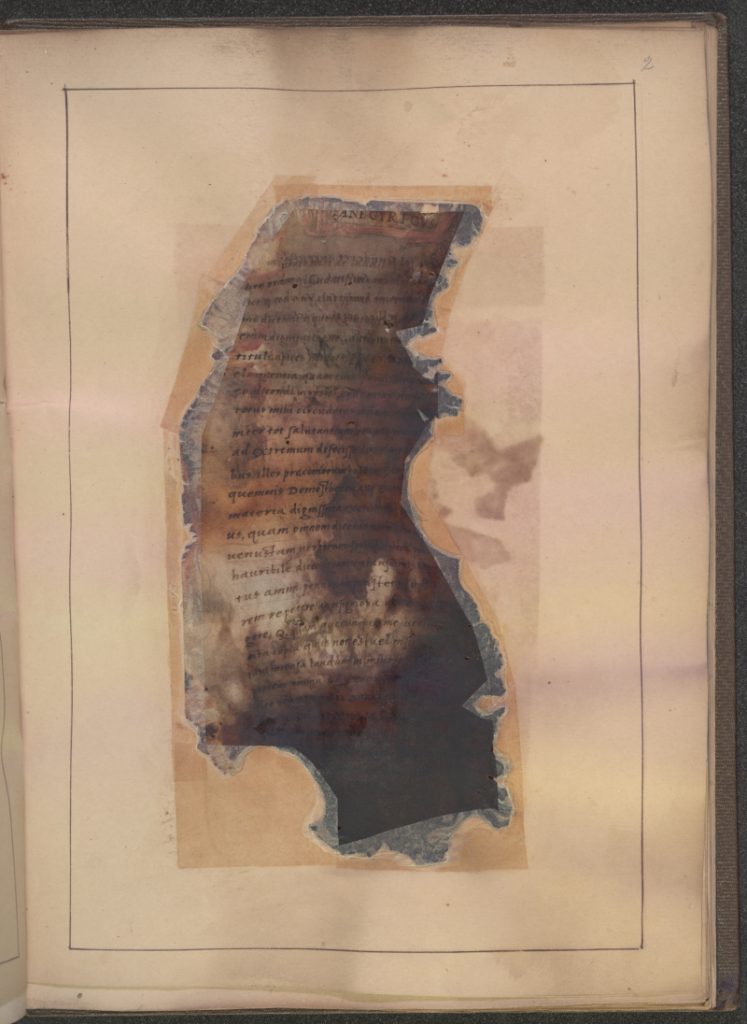 A charred manuscript fragment mounted in a paper frame. 